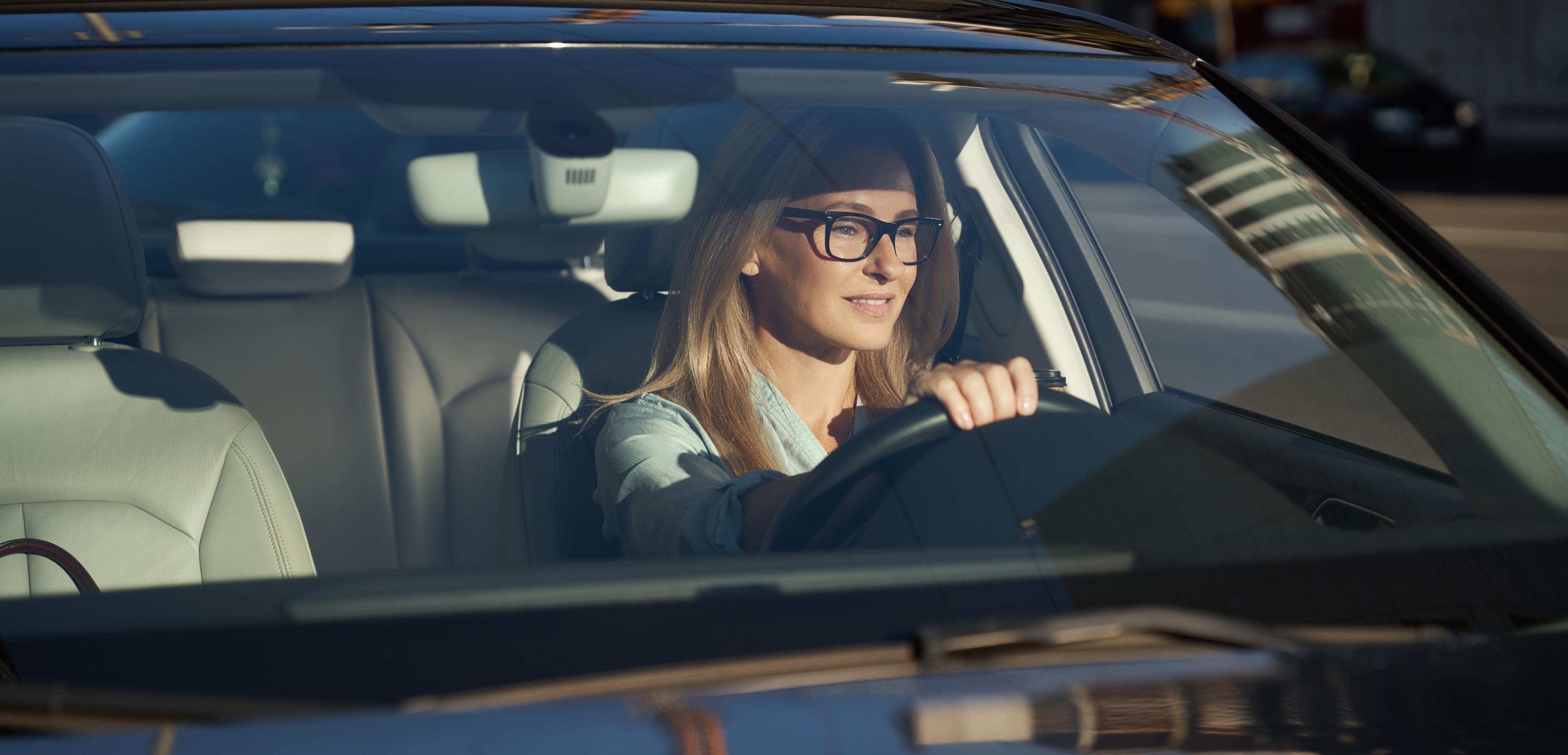 Frau und Mann beugen sich auf ein Auto und blicken zusammen in ein Tablet